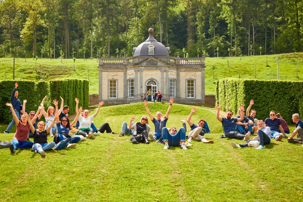 BP®-werknemers steken hun handen in de lucht en gaan op het gras bij een park zitten.