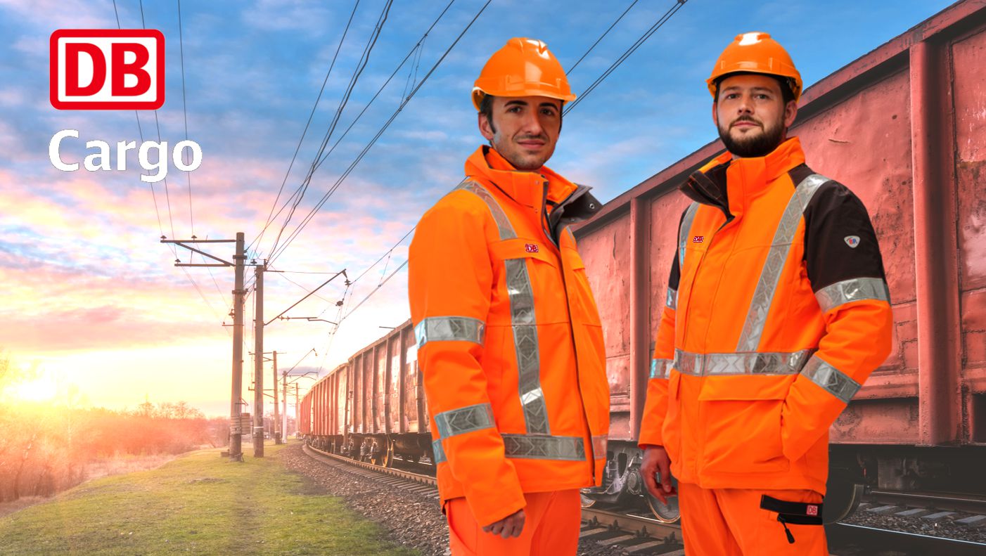 Zwei Männer mit orangefarbiger Warnschutzkleidung  stehen vor einem Bahngleis.