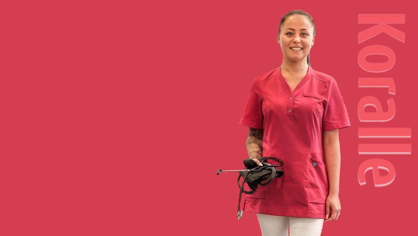 Een vrouw draagt een koraalkleurige tuniek en houdt een stethoscoop in haar hand.