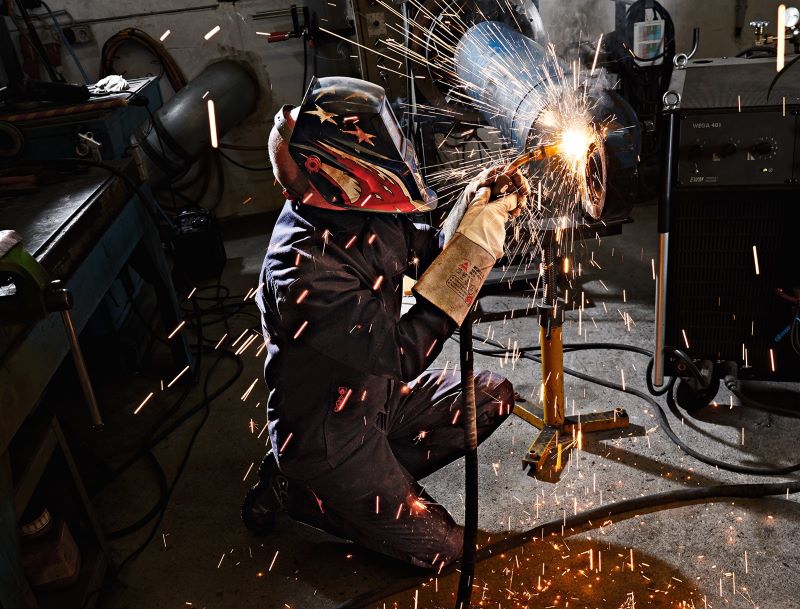 Le soudeur porte des vêtements de protection pour soudeurs et est en train de souder avec des étincelles visibles.
