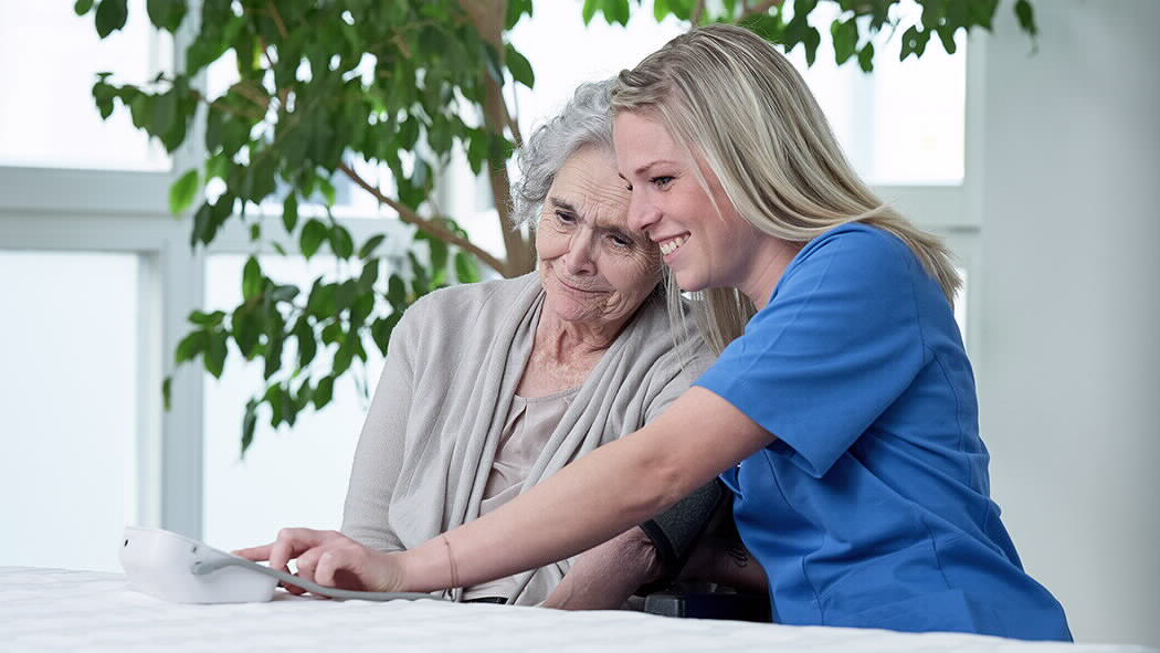Pflegerin hilft Seniorin. im Seniorenheim