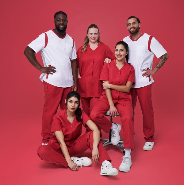 Ein Pflegeteam trägt rot weiße Uniformen. Es sind zwei Männer und drei Frauen zu sehen.