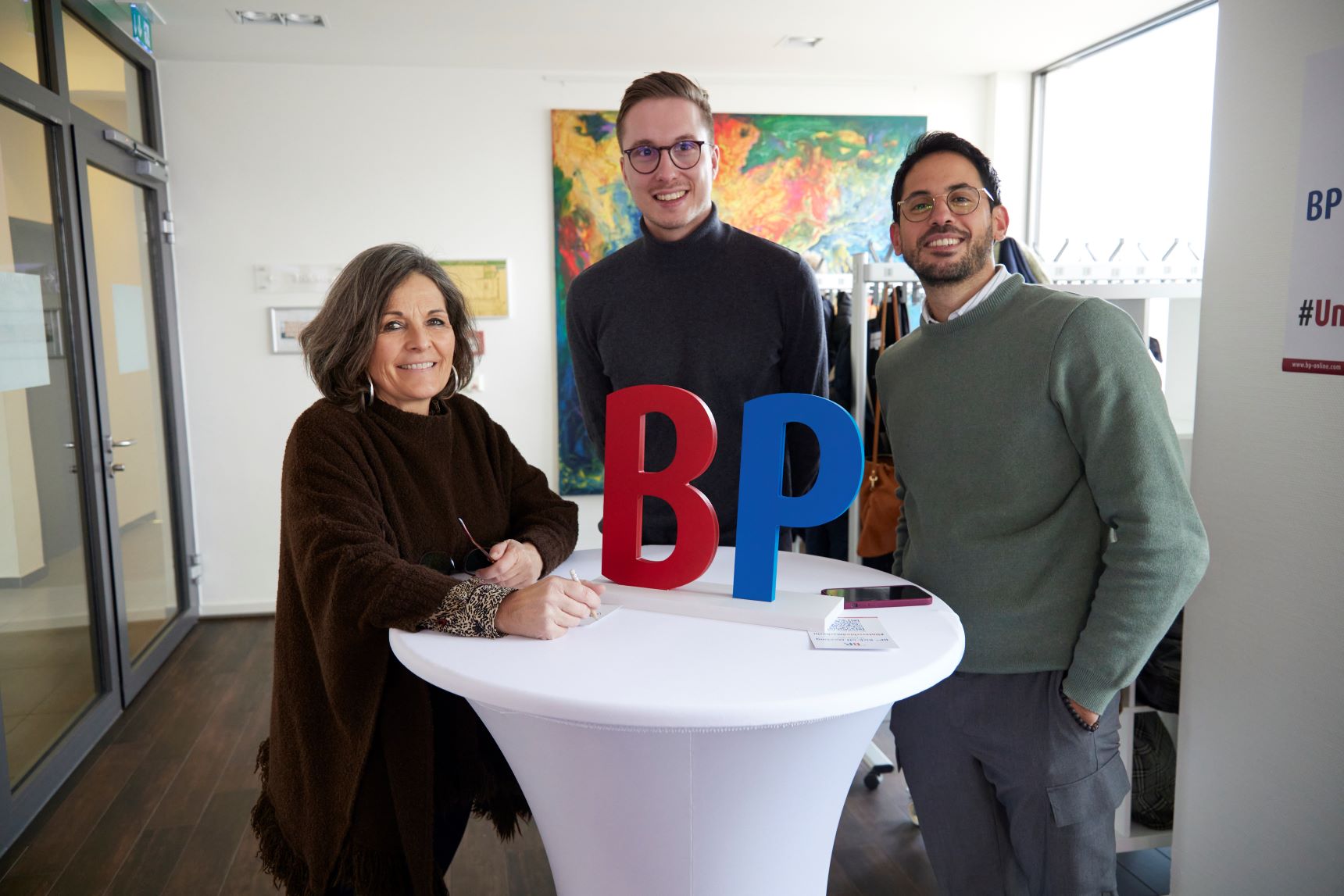 Twee BP®-werknemers en een vrouwelijke werknemer poseren voor de camera tijdens een bedrijfsevenement.