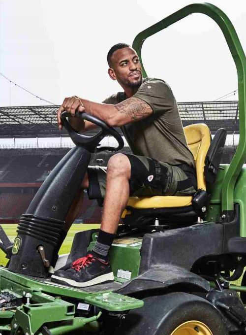 Un greenkeeper en tenue de travail tond la pelouse du Rheinenergiestadion.