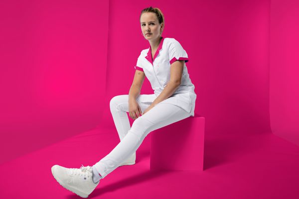Eine Pflegerin trägt eine weiße Hose und ein weiß Pinkes Kasack.