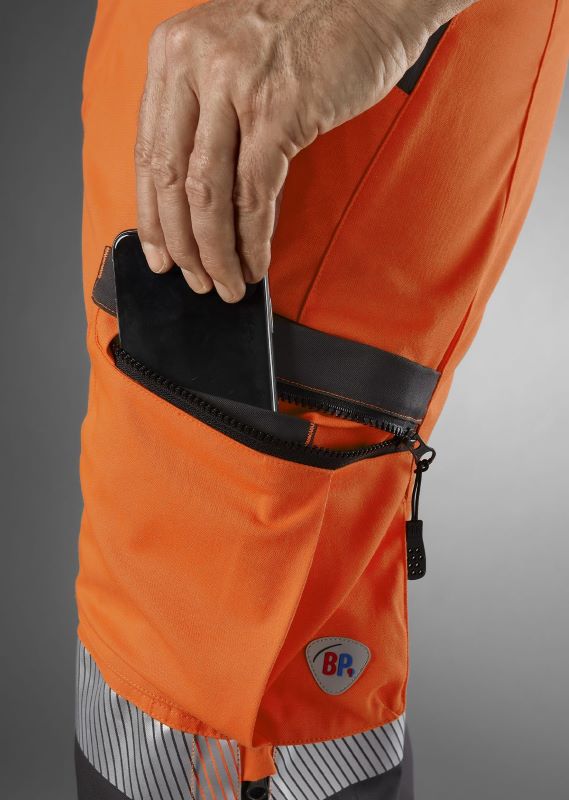 Smartphone wird in die dafür vorgesehene Tasche der Warnschutzhose gesteckt.