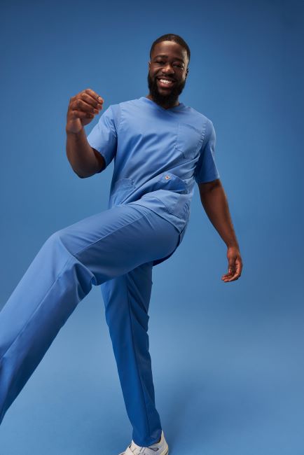 Tanzender Pfleger in hellblauer Pflegekleidung.
