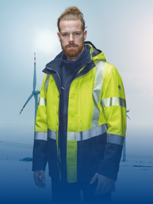 A man wears BProtected protective clothing and stands in front of a wind turbine.
