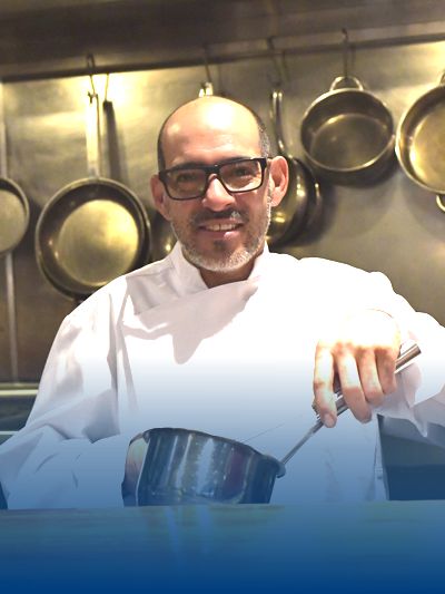 Een chef-kok voor fijnproevers draagt een witte koksjas in de keuken.