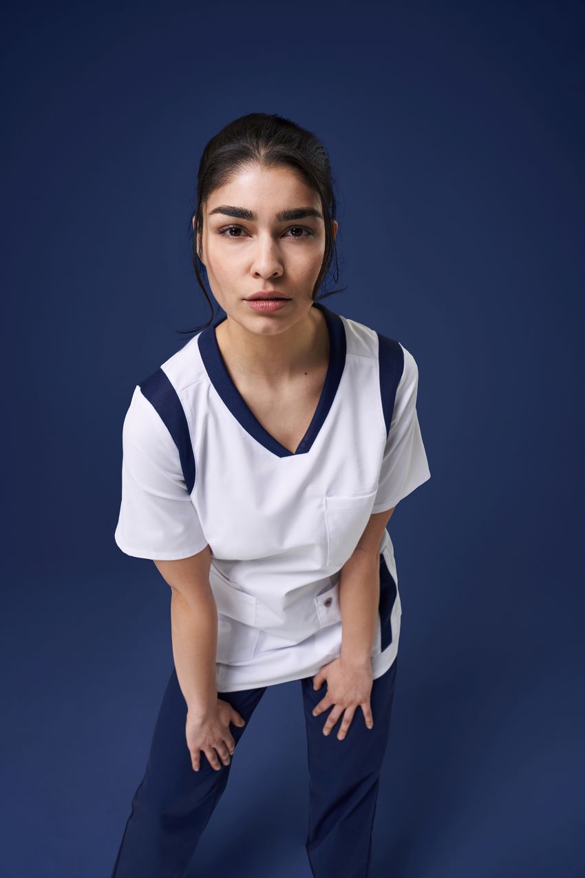 Un mannequin porte des vêtements de travail à la mode pour les soins et regarde la caméra.