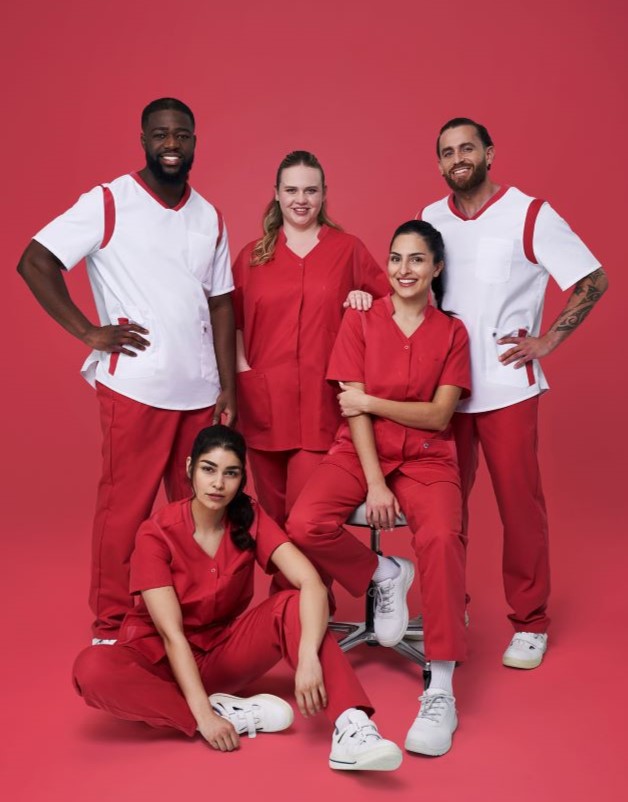 Ein Pflegeteam trägt rot weiße Uniformen. Es sind zwei Männer und drei Frauen zu sehen.