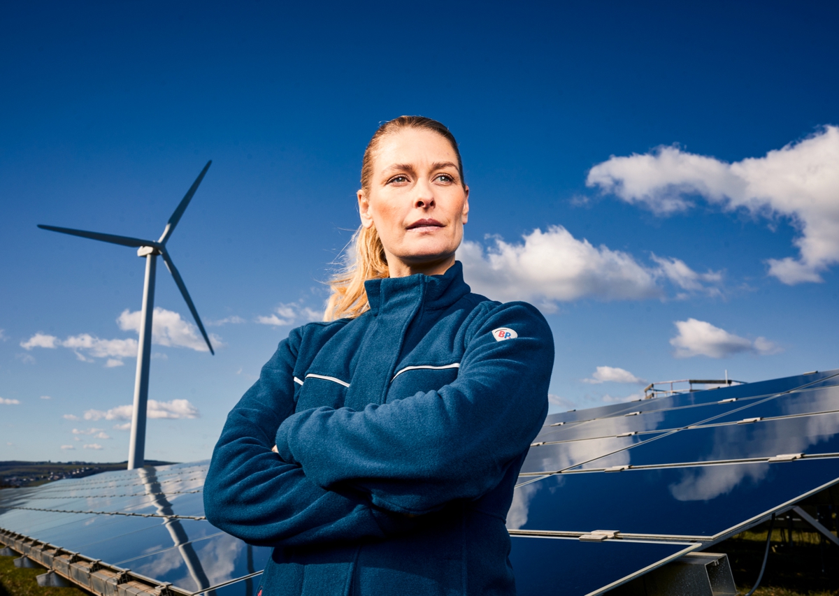 Woman wearing BP® lightweight multinorm jacket APC1 in front of a wind turbine