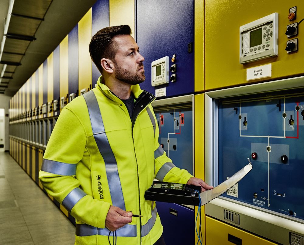 Ein Elektriker mit Schutzkleidung nach EN 1149-5 prüft Schalter.