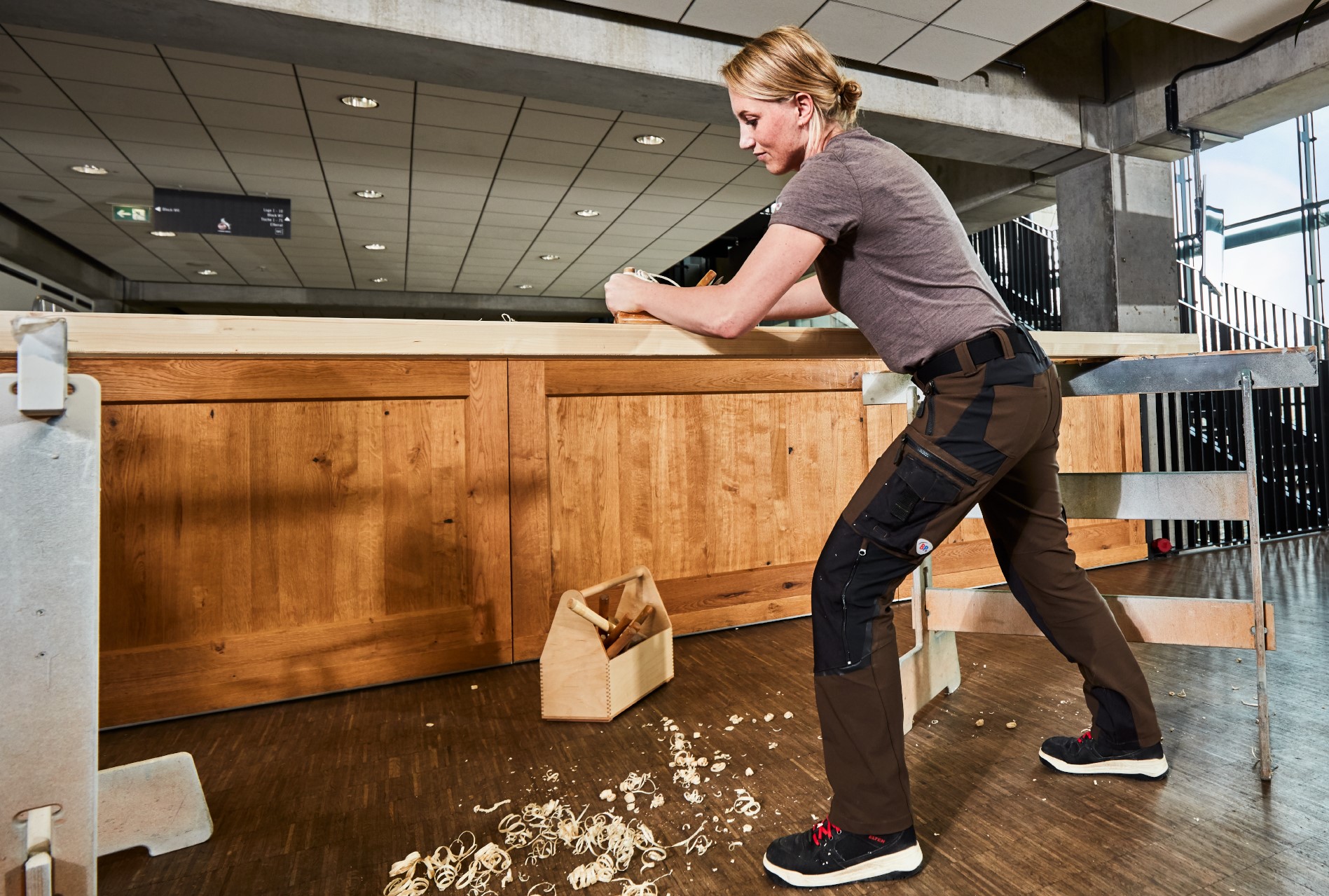 A craftswoman sands wood in BP® workwear.
