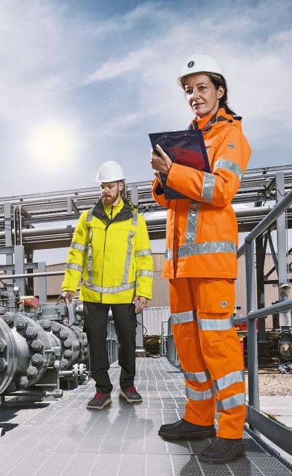 Eine Frau und ein Mann in Arbeitskleidung kontrollieren Prozesse in  der Chemieindustrie.