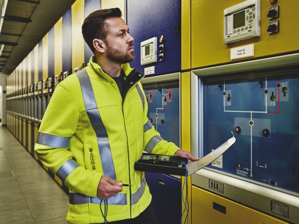 Ein Elektriker mit Schutzkleidung nach EN 1149-5 prüft Schalter.