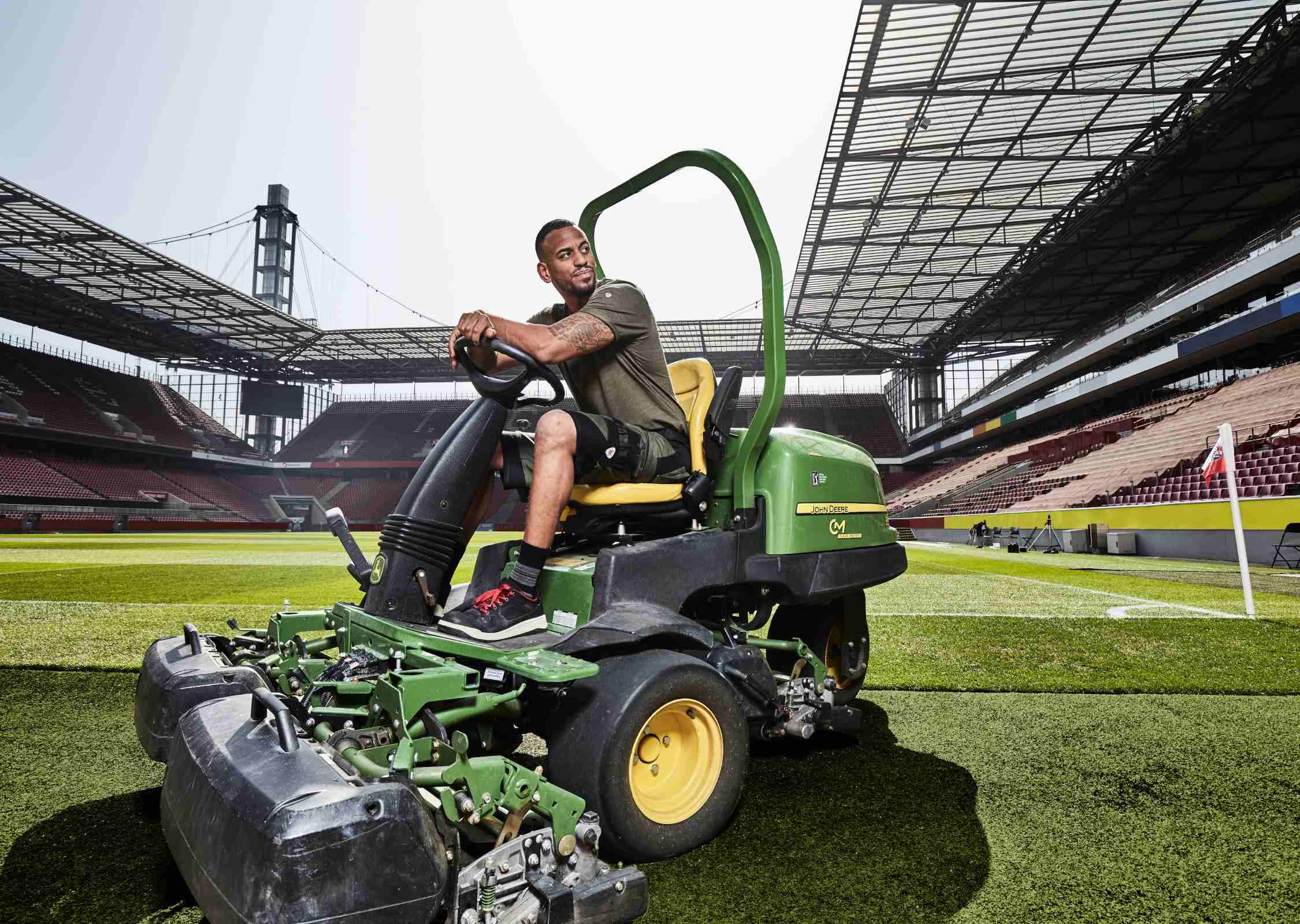 A greenkeeper in work clothes mows the grass at the Rheinenergiestadion.