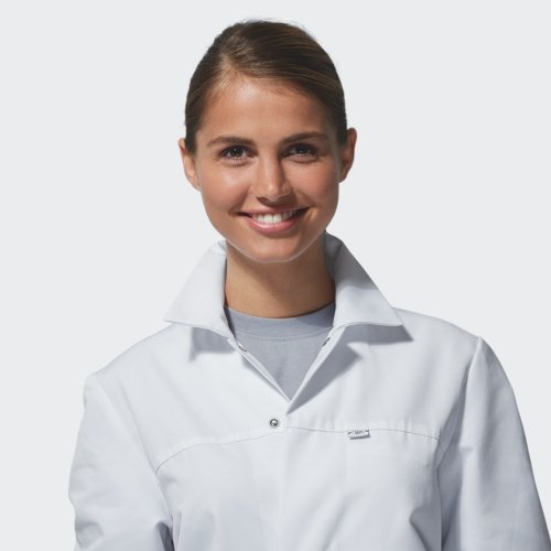 Eine Frau trägt weiße HACCP Arbeitskleidung und lächelt in die Kamera.