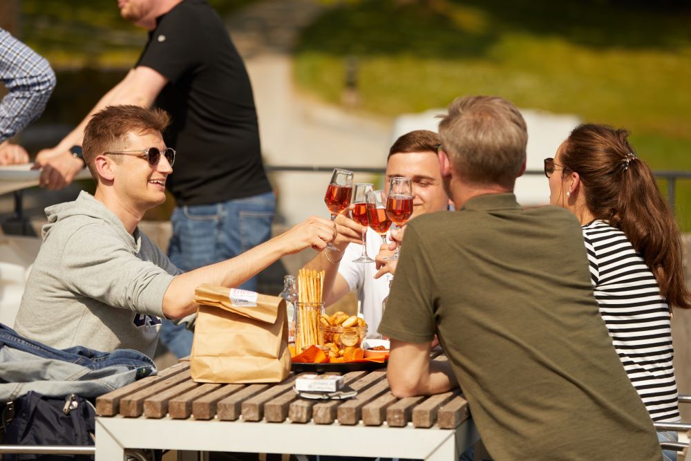 BP Mitarbeiter sitzen im Freien und stoßen mit einem Wein an.