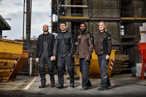 Drei Handwerker und eine Handwerkerin auf einer Baustelle tragen BP® Arbeitskleidung.