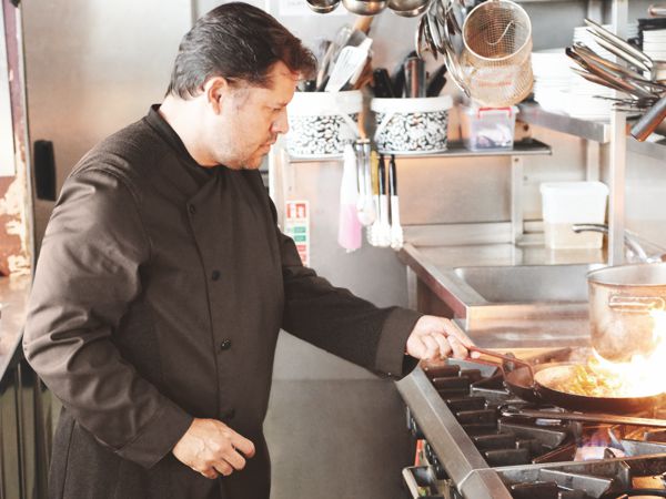 Koch ist in einer Küche am braten mit einer Kochjacke.