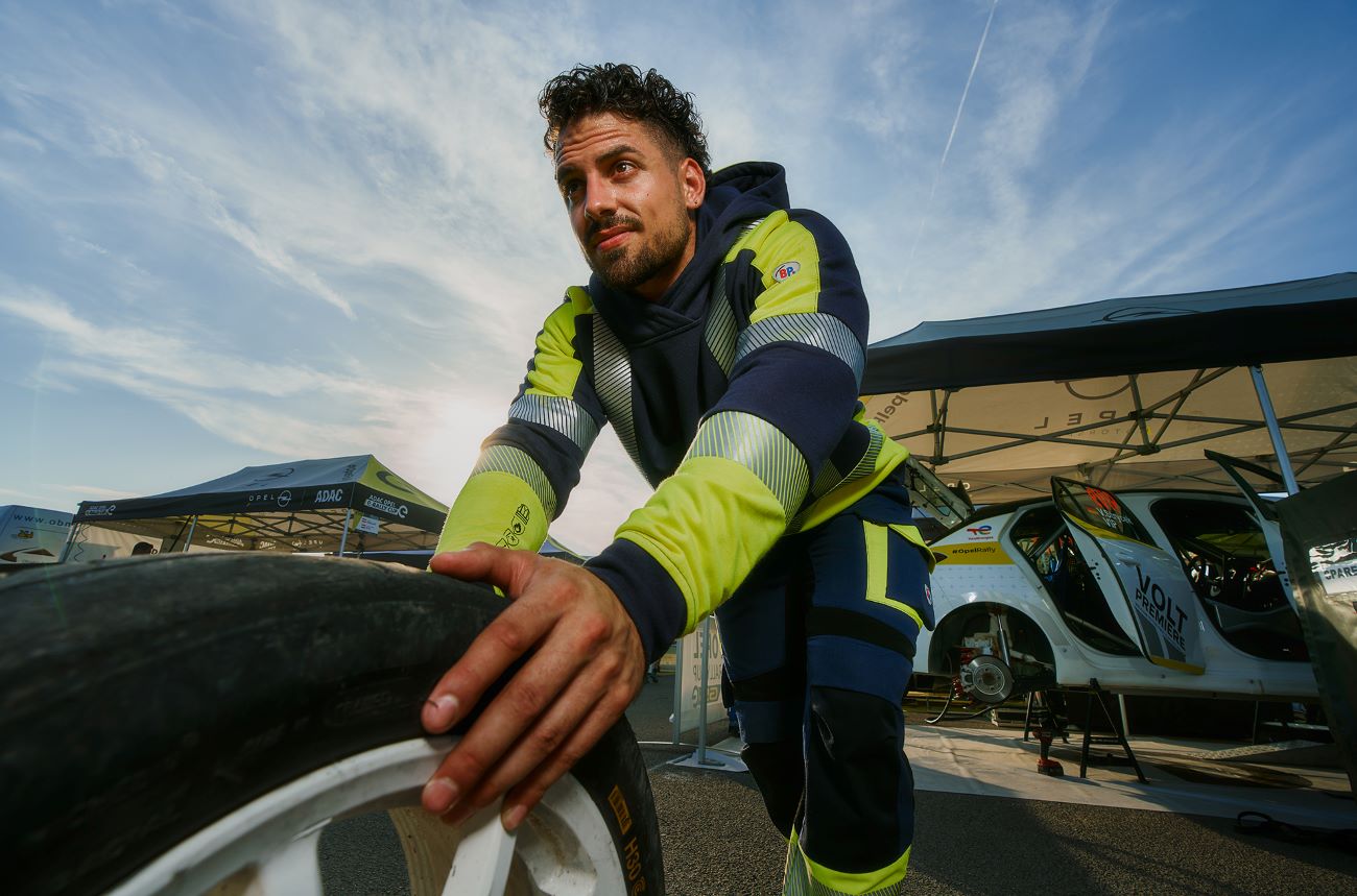 Automechaniker in Schutzkleidung wechselt Reifen bei E-Rennauto.