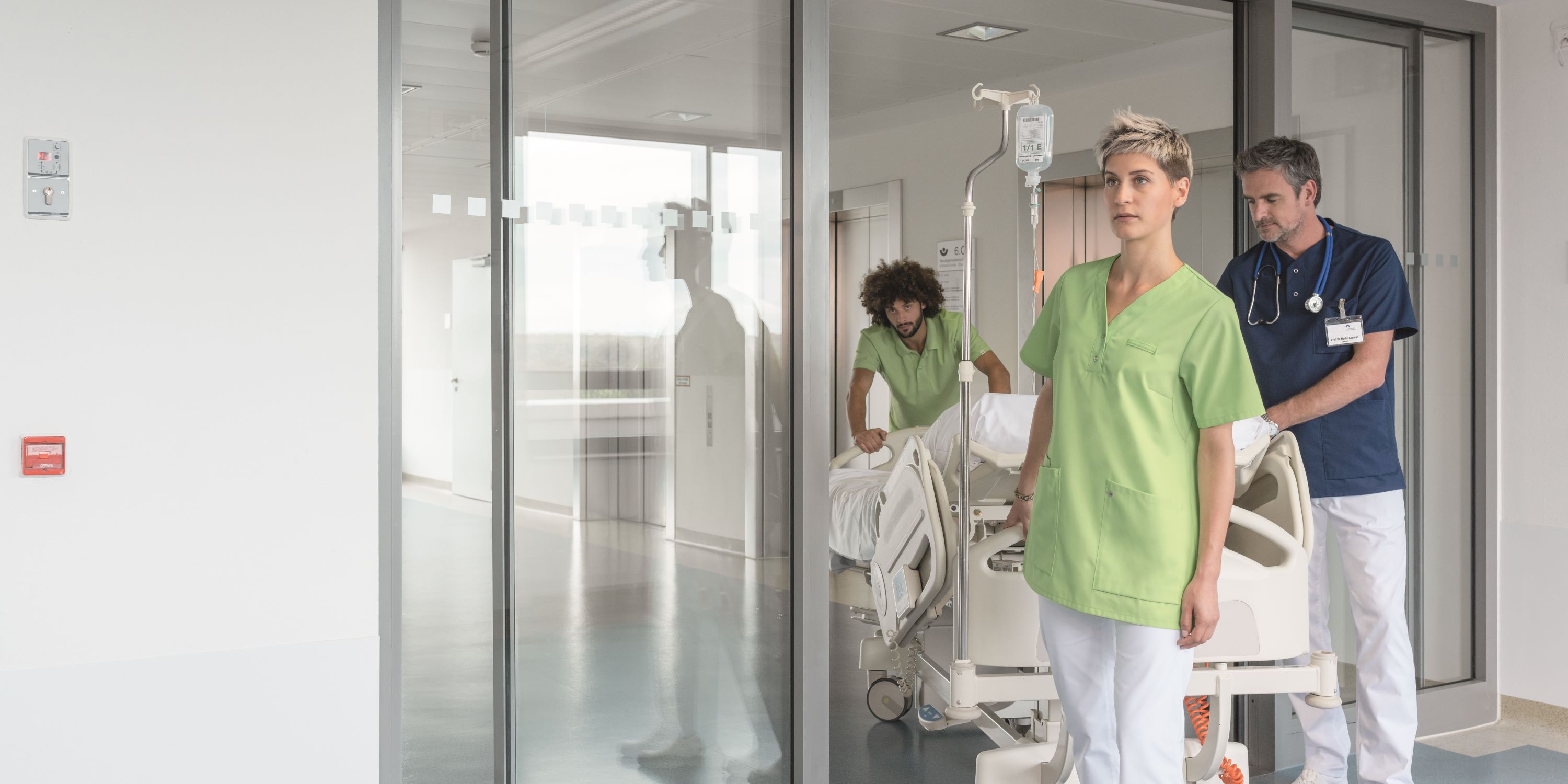 Le personnel hospitalier pousse un lit d'hôpital avec un uniforme de travail assorti.
