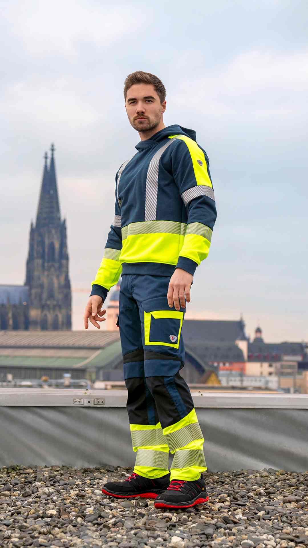 Ein Mann trägt MultiProtectPlus Kleidung und steht auf einem Dach mit dem Kölner Dom im Hintergrund.