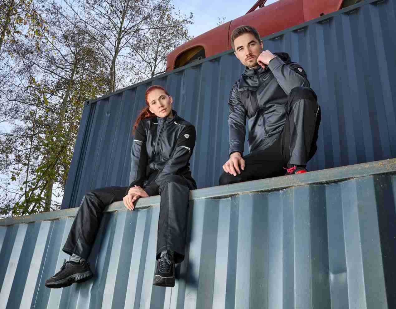 Eine Frau und ein Mann sitzen auf einem Container mit BP® Arbeitskleidung.