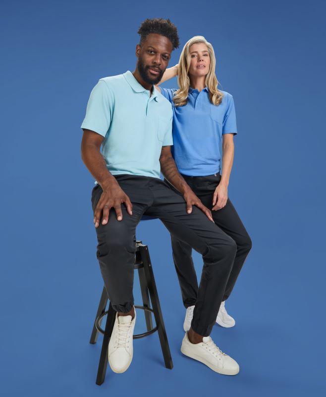 Eine Frau und ein Mann tragen BP®  poloshirts in hellblau. Der Mann sitzt auf einem Hocker.