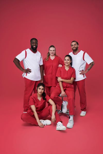 Pflegeteam aus Männern und Frauen in rot-weißem Pflegeoutfit.