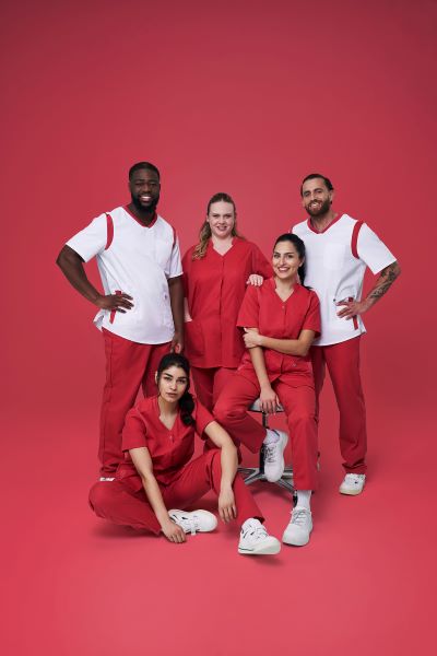 Ein Pflegeteam trägt rot weiße Uniformen. Es sind zwei Männer und drei Frauen zu sehen.