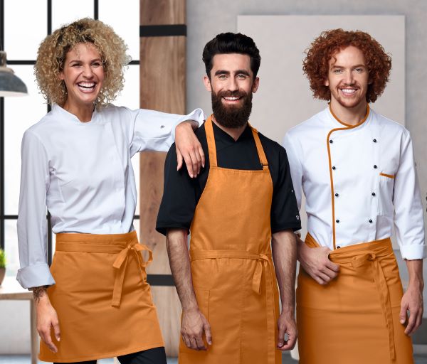 Zwei Männer und eine Frau tragen weiße Gastrokleidung und lächeln in die Kamera.