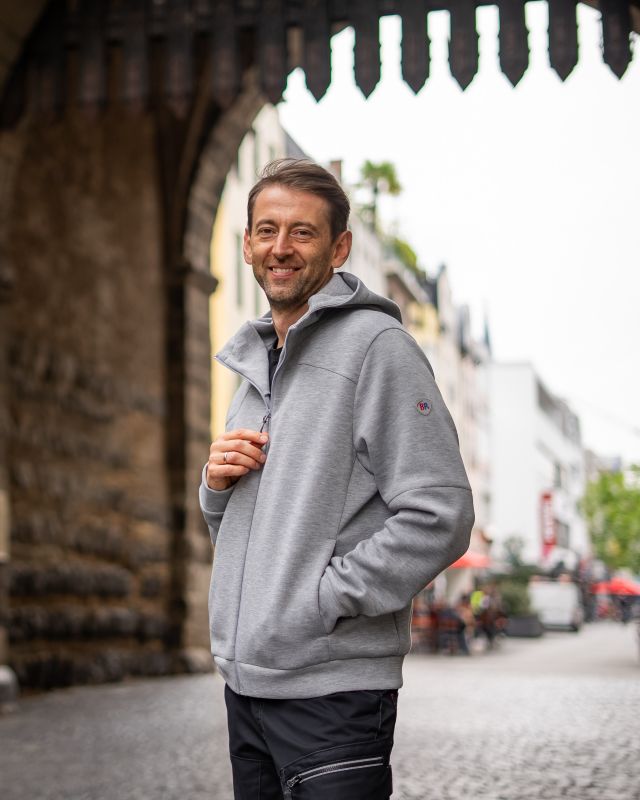 Mann in grauer Kapuzen-Sweatjacke vor dem Eigelsteintor in Köln.