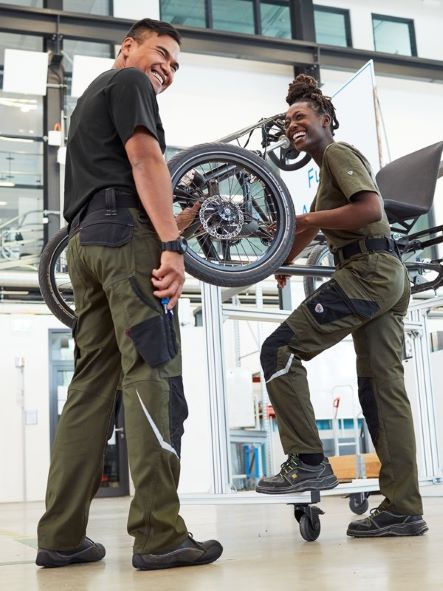 Two industrial workers in work clothes assemble a car.