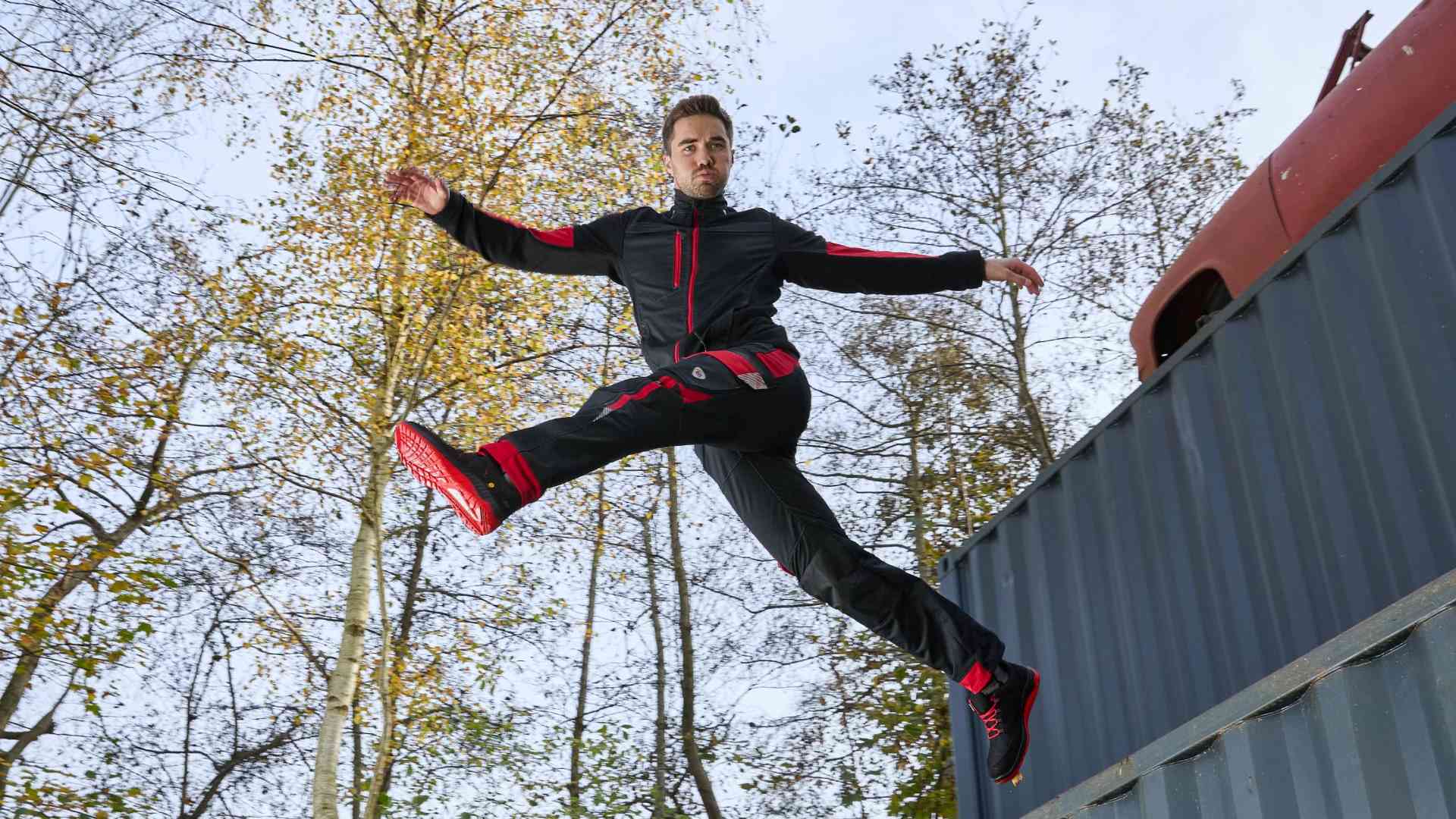 A man jumps from a container with his legs apart, wearing BP® work clothes.