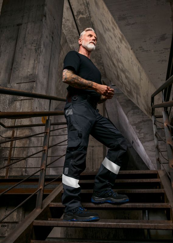 Arbeiter in dunkler Arbeitskleidung mit Reflexstreifen.