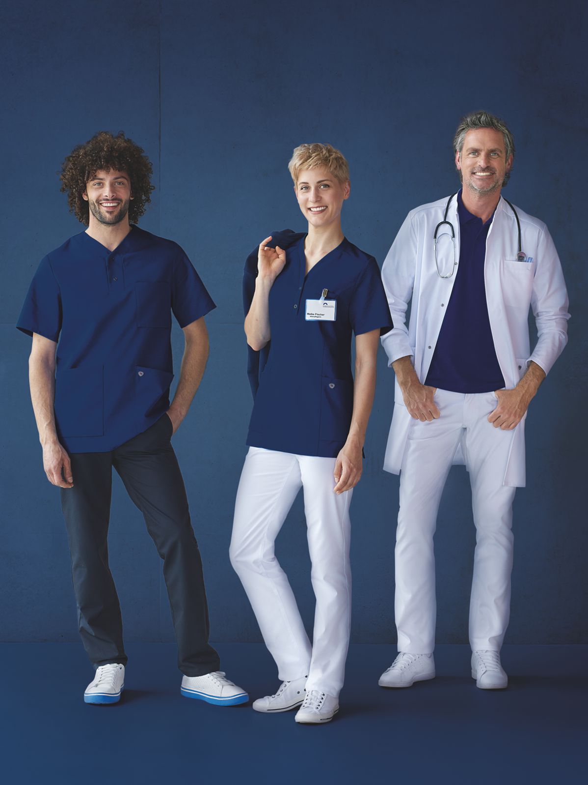 Pflegepersonal und Arzt in nachtblauer und weißer Arbeitskleidung.