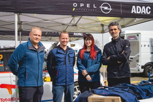 Une équipe de service E-Rally de quatre personnes en tenue de travail.