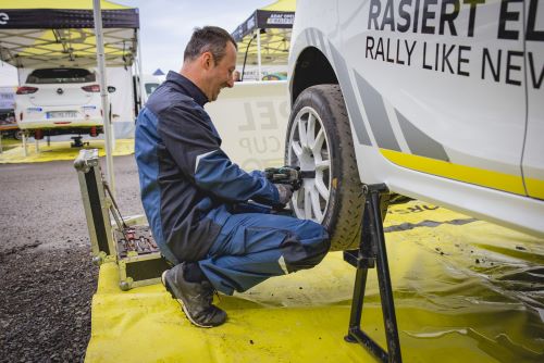 Automechaniker in Schutzkleidung wechselt Reifen bei E-Rennauto.