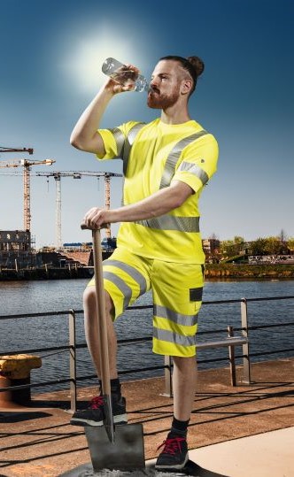 Bauarbeiter am Rheinufer trinkt aus Wasserflasche.