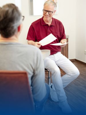 Ein Arzt spricht mit seinem Patienten in einem Praxisoutfit von BP®.