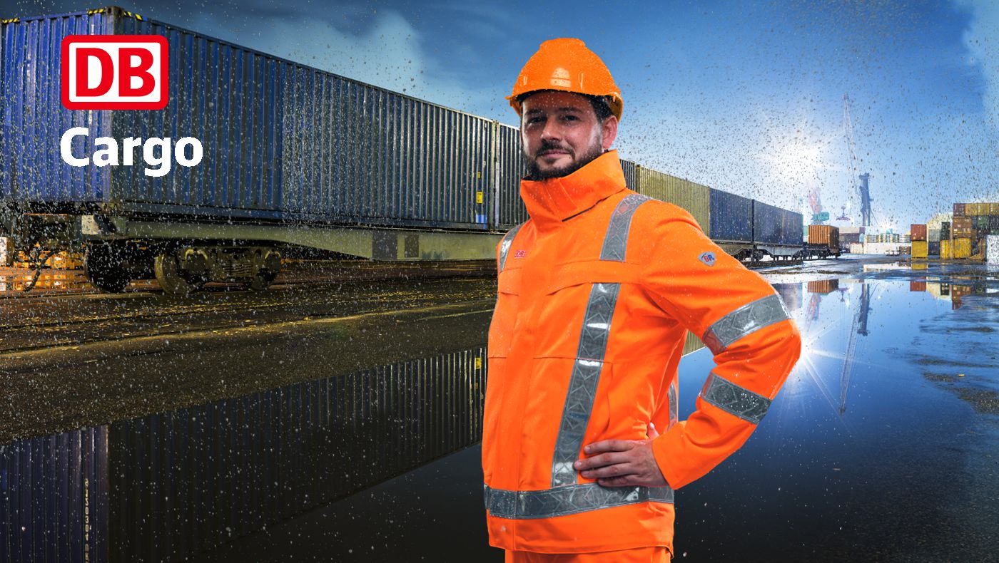 Mann steht auf genässtem Boden mit orangefarbiger Warnschutzkleidung in einem Containerhafen.