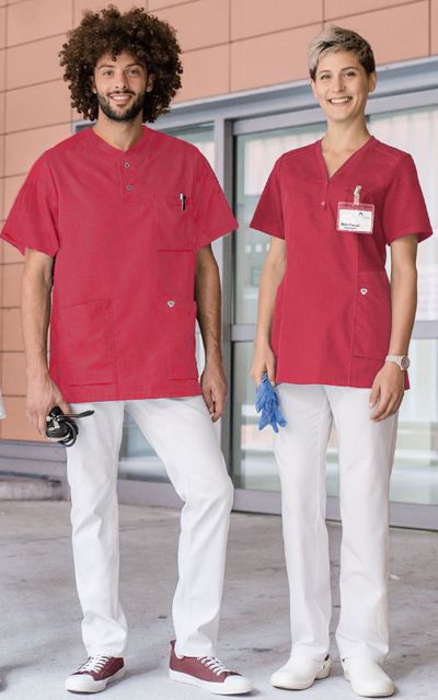 Pflegefachfrau und Pflegefachmann stehen in Krankenhausuniform vor Klinikeingang.