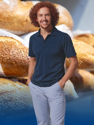 Ein Bäcker trägt Arbeitskleidung. Im Hintergrund sind Brote zu sehen.