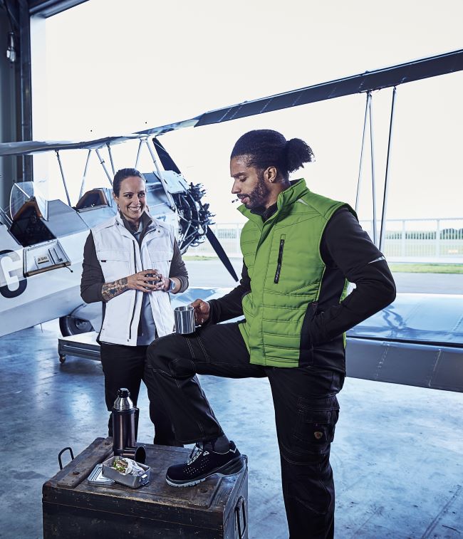 Mechaniker*innen in Arbeitskleidung in einem Flugzeughangar.