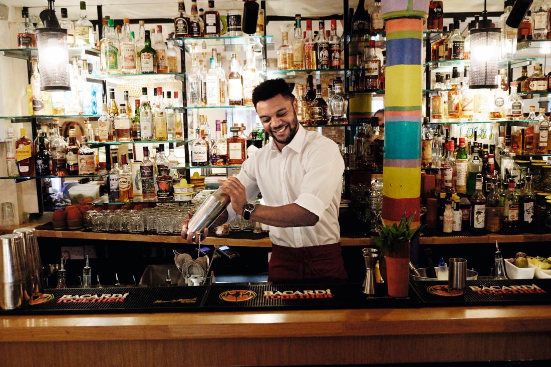 Barman in wit overhemd mixt cocktail.
