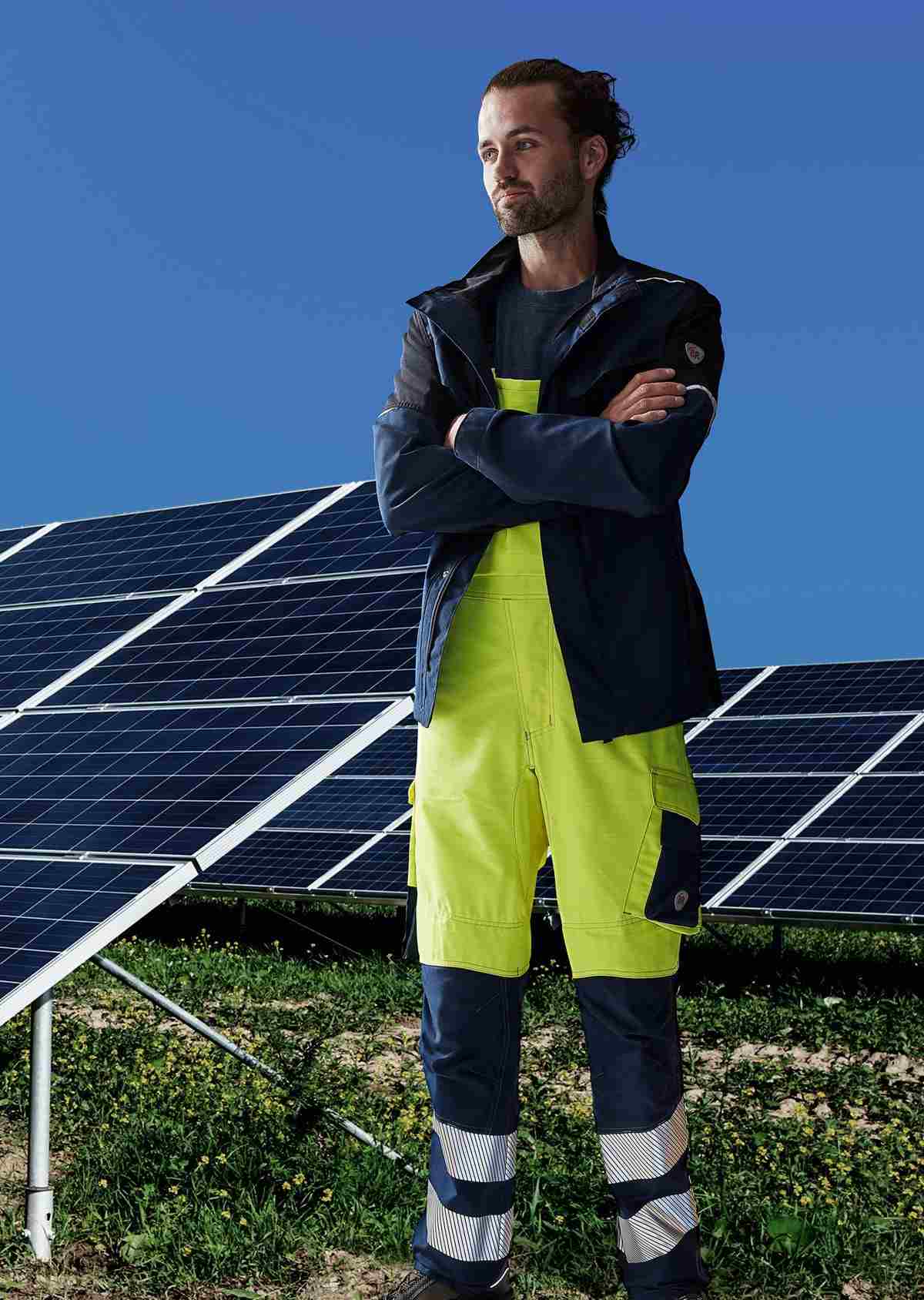 EIn Mann steht vor einer Solaranlage und trägt eine Multinorm Jacke von BP®.