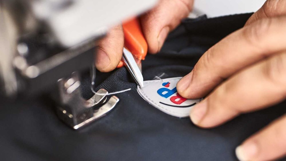 Une couturière coud le logo BP sur un tissu.