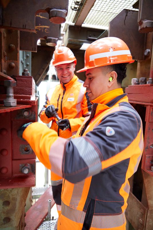 Zwei Instandsetzungstechniker bei DB InfraGO führen Wartungsarbeiten an der Bahnstrecke durch.